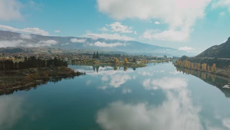 Scenic-aerial-view-of-a-calm-and-reflective-Lake-Dunstan-with-clouds-showing-on-surface-of-water-in-Cromwell-town-in-Central-Otago-region-of-South-Island,-New-Zealand-Aotearoa