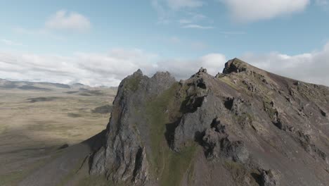 Cumbre-De-Montaña-Rocosa-En-Suave-Paralaje-Drone,-Cielo-Azul-Con-Nubes