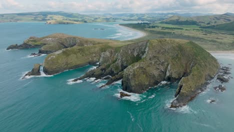 Panoramic-aerial-view-of-rugged-and-rocky-landscape-stretching-into-the-ocean-in-the-remote-wilderness-of-Cannibal-Bay,-Catlins,-South-Island-of-New-Zealand-Aotearoa