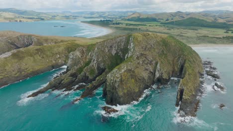 Aerial-drone-view-of-stunning-Cannibal-Bay-with-rugged-and-wild-coastal-landscape-and-turquoise-ocean-water-in-Catlins,-South-Island-of-New-Zealand-Aotearoa