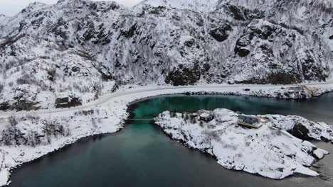 Drohnenansicht-In-Der-Gegend-Von-Tromso-Im-Winter,-Die-über-Eine-Hängende-Holzbrücke-Zu-Einer-Insel-Mit-Klarem-Blauen-Meer-In-Norwegen-Fliegt