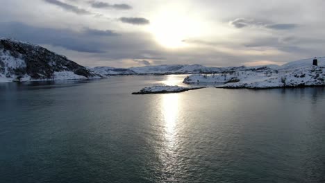 Drone-view-in-Tromso-area-in-winter-flying-over-a-snowy-islands-surrounded-by-the-sea-in-Norway