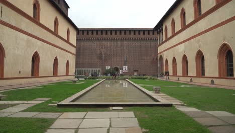Inner-Yard-of-Sforzesco-Castle-with-Water-Pool-with-People-Walking-Around-near-Defense-Wall