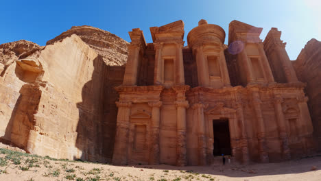 Slow-pan-right-shot-of-tourists-at-Ad-Deir-door,-The-Monastery,-Petra,-Jordan