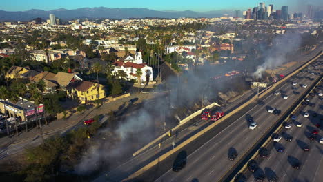 Aerial-view-around-firefighters-extinguishing-a-fire,-threatening-a-freeway-in-LA