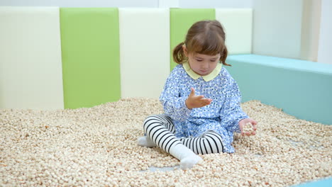 Kindercafé---3-jähriges-Kleines-Mädchen-Gemischter-Abstammung,-Das-Im-Indoor-Spielzimmer-Im-Sandbecken-Mit-Holzklötzen-Spielt