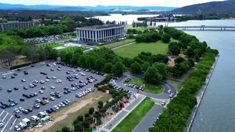 Drone-aerial-shot-of-carpark-Lake-Burley-Griffin-National-library-Questacon-Parliamentary-triangle-zone-politics-travel-tourism-state-circle-technology-flags-Canberra-ACT-Australia-4K