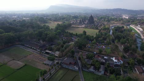 Aerial-view-of-a-group-of-cyclists-passing-the-edge-of-the-Prambanan-temple,-which-is-a-cadi-with-Hindu-religious-patterns