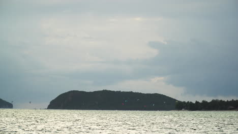 People-kitesurfing-in-the-distance-in-a-beach-of-Koh-Phangan,-Thailand