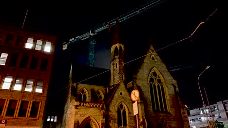 Eine-Parallaxenaufnahme-Der-Unitarian-Church-Dublin-Vor-Dem-Hintergrund-Moderner-Turmdrehkrane-Bei-Nacht