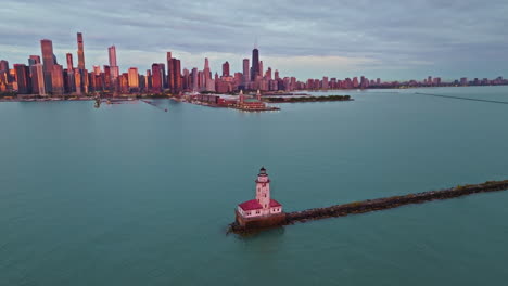 Aerial-view-around-the-sunlit-Chicago-Harbor-Lighthouse-with-skyline-background