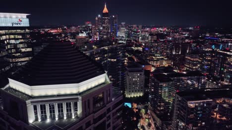 Aerial-backwards-shot-over-lighting-Cityscape-of-Atlanta-at-night-in-Georgia---PWC-Tower-and-Bank-of-America-Plaza-in-Background