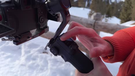 Close-Up-View-Of-Fingers-Tapping-On-Gimbal-Screen-Outside-With-Snow-On-The-Ground