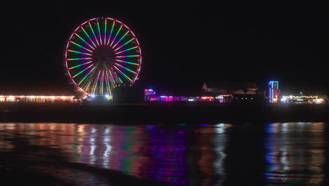 Big-Wheel-ride-and-amusements-at-night-with-lights-reflecting-from-the-incoming-tide-at-Central-Pier,-Blackpool,-Lancashire,-England,-UK