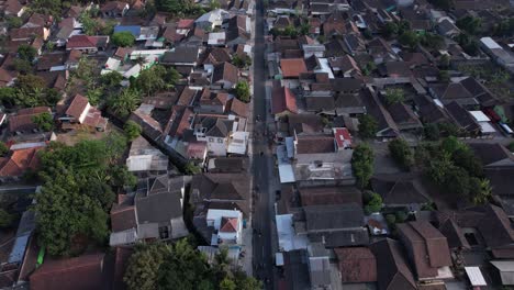 aerial-view-of-a-group-of-cyclists-passing-through-dense-villages-in-Klaten,-Indonesia