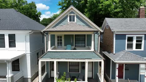 Klassisches-Blaues-Amerikanisches-Haus-Mit-Veranda-Und-Satteldach,-Eingebettet-Zwischen-ähnlichen-Häusern