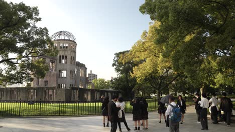 Lokale-Schulkinder-Fotografieren-Neben-Dem-Atombomben-Dom-Denkmal-In-Hiroshima,-Während-Das-Goldene-Stundenlicht-Auf-Bäumen-Leuchtet