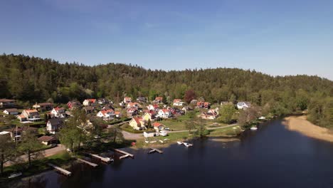 Approach-Drone-Shot-of-a-little-Village-nearby-a-lake-in-Sweden