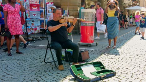 older-man-sitting-on-chair-playing-violin-on-the-city-market-square-in-Strasbourg
