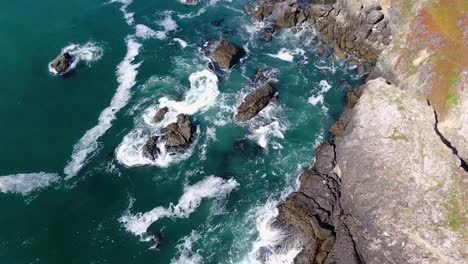 Aerial-top-view-video-capturing-the-beauty-of-a-blue-rocky-coast-with-waves-gently-crashing-against-a-rugged-shoreline-in-Bodega-Bay,-Gualala-Coast-California