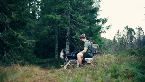 European-Backpacker-Sitting-And-Resting-On-Rock-With-Alaskan-Malamute-Dog-In-Indre-Fosen,-Norway