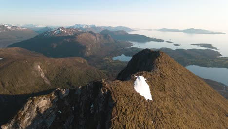 Drohnenvideo-Des-Majestätischen-Berges-Midsundtrappene-Mit-Ein-Paar-Wanderern-Auf-Dem-Bergrücken,-Die-Den-Wunderschönen-Blick-Auf-Das-Norwegische-Meer-Genießen