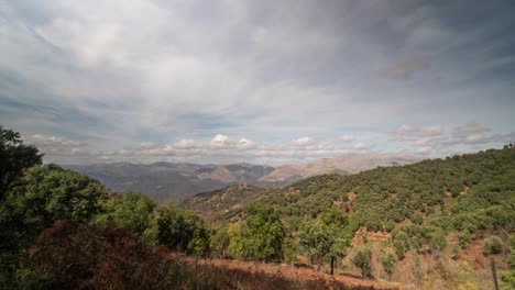 Green-trees-and-rocky-mountain-of-Spain-with-flowing-clouds-above,-time-lapse