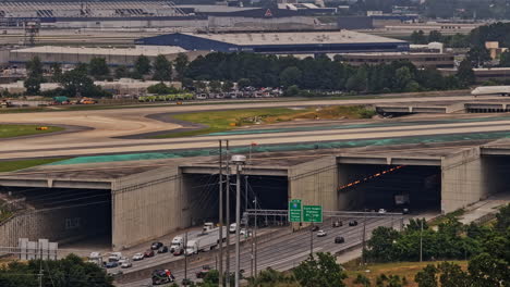 Atlanta-Georgia-Aerial-v944-birds-eye-view-of-bridge-runway-structures-over-busy-i-285-highway,-tilt-up-reveals-airport-activities-and-downtown-cityscape---Shot-with-Mavic-3-Pro-Cine---May-2023
