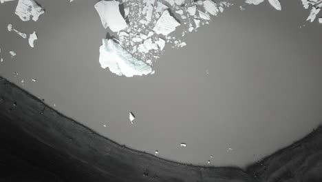 Aéreo-De-Arriba-Hacia-Abajo-Dramáticos-Icebergs-Flotando-En-El-Agua,-Lago-Jokulsarlon,-Paisaje-De-Nieve-De-Clima-Natural,-Islandia