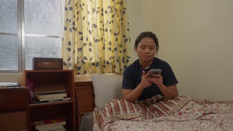 Asiatisches-Indonesisches-Mädchen-Emotional,-Nachdem-Sie-Im-Schlafzimmer-Eine-SMS-Geschrieben-Hat