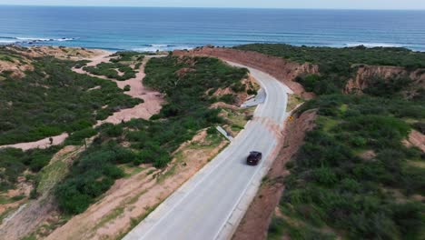 El-Dron-Desciende-Inclinándose-Hacia-Arriba-Para-Revelar-La-épica-Playa-De-Cabo-Pulmo-Mientras-El-SUV-Corre-Por-La-Carretera.