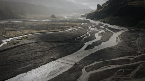 Cinematic-aerial-thor-valley,-glacial-river-flowing-through-black-volcanic-scenery,-bridges-for-river-crossings,-thorsmörk-Iceland