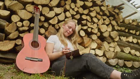 Beautiful-country-girl-songwriter-composes-lyrics-rustic-log-scene