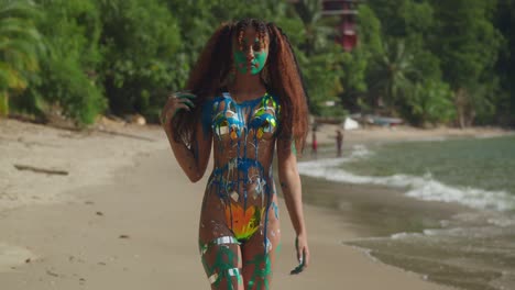 Body-paint-covered-girl-walking-on-a-tropical-beach-in-the-Caribbean-with-ocean-waves-in-the-background