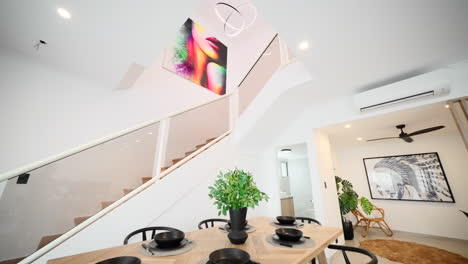 Modernes-Wohn--Und-Esszimmer-Mit-Innenraum-Mit-Treppe,-überhängender-Kronleuchter-Pendelleuchte-Und-Farbenfrohen-Kunstwerken