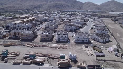 A-captivating-drone-shot-pulls-away-from-a-home-construction-site,-with-the-camera-tilting-to-reveal-the-vastness-of-ongoing-construction,-showcasing-the-scale-and-dynamism-of-the-entire-project