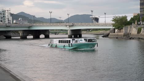 Aqua-Net-Fähre,-Die-Entlang-Des-Flusses-Motoyasu-Fährt,-Vorbei-An-Der-Atombombenkuppel-In-Hiroshima-Mit-Der-Aioi-Brücke-Im-Hintergrund
