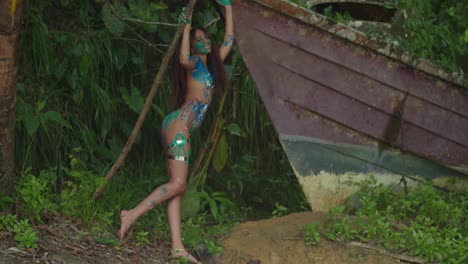 A-girl-in-body-paint-stands-next-to-an-abandoned-boat-in-nature