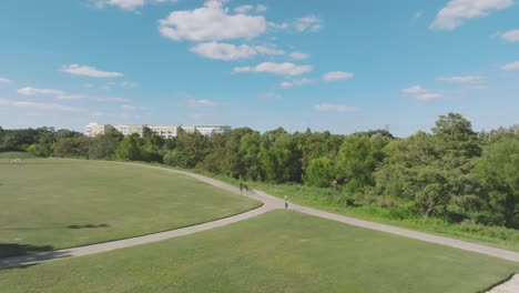 An-aerial-view-of-a-young-woman-taking-a-walk-through-Eleanor-Tinsley-Park-on-a-sunny-day-with-white-clouds-in-Houston-Texas