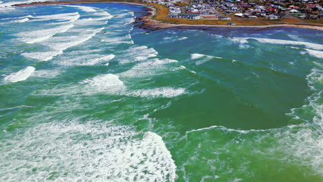 High-angle-drone-view-of-L'Agulhas-coastal-village-with-waves-rolling-in