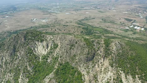 Pull-away-drone-shot-retreating-slowly-from-the-mountain-showing-the-rest-of-the-different-surrounding-landforms-like-the-fields-and-plains-in-the-nearby-town-of-Rupite-in-Petrich,-Bulgaria