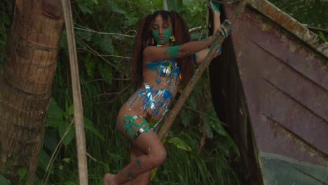 Light-skin-woman-in-body-tape-and-paint-in-nature-next-to-an-abandoned-boat
