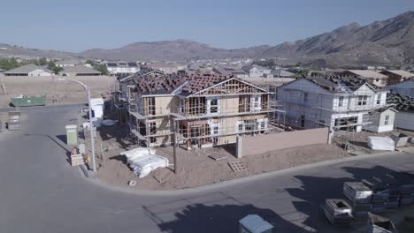 From-a-distance,-a-drone-meticulously-inspects-a-partially-built-house-on-a-construction-site,-offering-a-comprehensive-view-of-the-ongoing-progress-in-residential-development