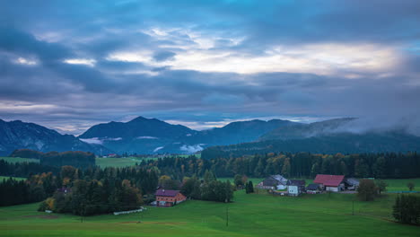 Timelapse-of-clouds-passing-over-Europen-village-autumn-field-landscape-in-the-evening,-Austrian-Alps-remote-and-scenic-town-with-mountain-in-the-background,-Europe