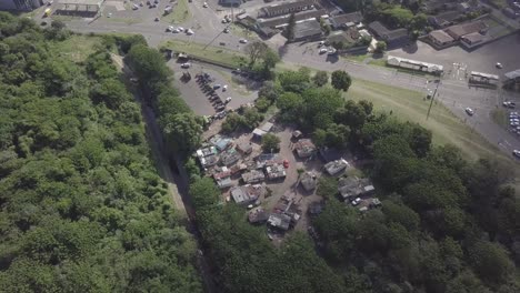 Drohne-Schwebt-über-Einem-Informellen-Siedlungsbesetzerlager-Auf-Der-Klippe,-Umgeben-Von-Buschigen-Bäumen