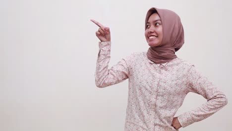 Happy-Wow-Excited-Young-Asian-muslim-woman-standing-while-pointing-and-presenting-sideways