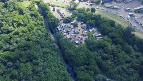 Drone-flying-away-from-an-informal-settlement-squatter-camp-surrounded-by-bushy-trees-and-a-canal