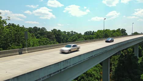 Descending-drone-shot-of-cars-on-bridge-and-forest-landscape-in-the-valley-in-Atlanta-City-Suburb