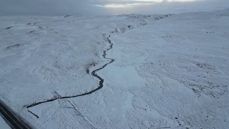Snowy-sunrise-of-a-stream-in-the-North-of-Iceland-in-the-winter,-aerial