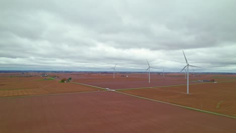 Luftaufnahme-Von-Windkraftanlagen-Inmitten-Eines-Bepflanzten-Feldes,-Das-Alternative-Energie-Erzeugt